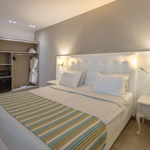 Double bed with bedside tables with wall-mounted reading lights and open wardrobe