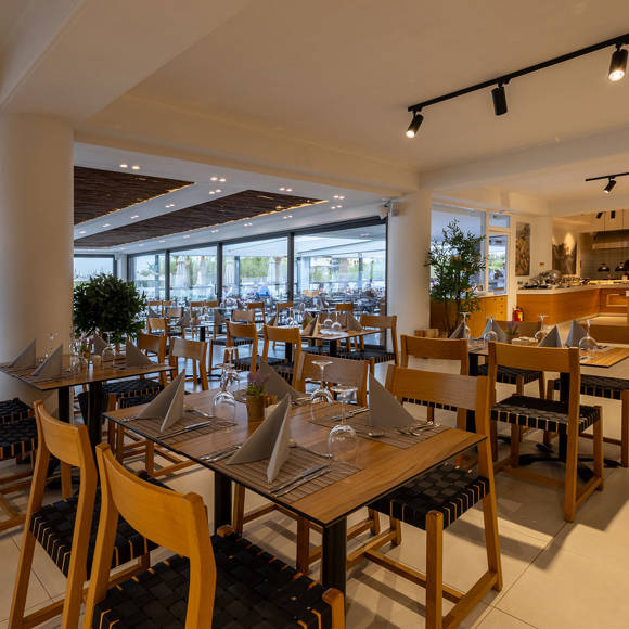 Cozy restaurant with set tables, wooden furniture and a visible buffer counter in the background