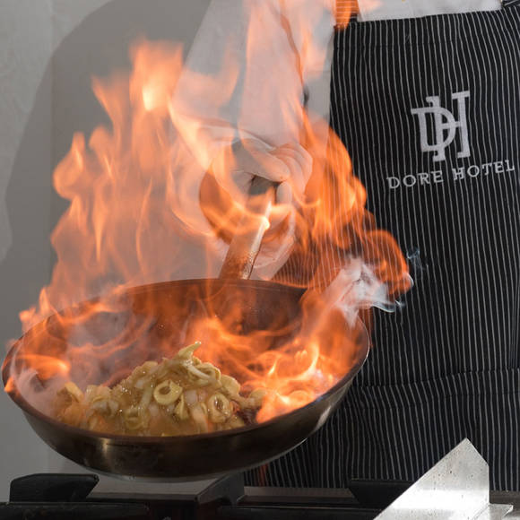 Chef flampeing pasta in a fiery pan 