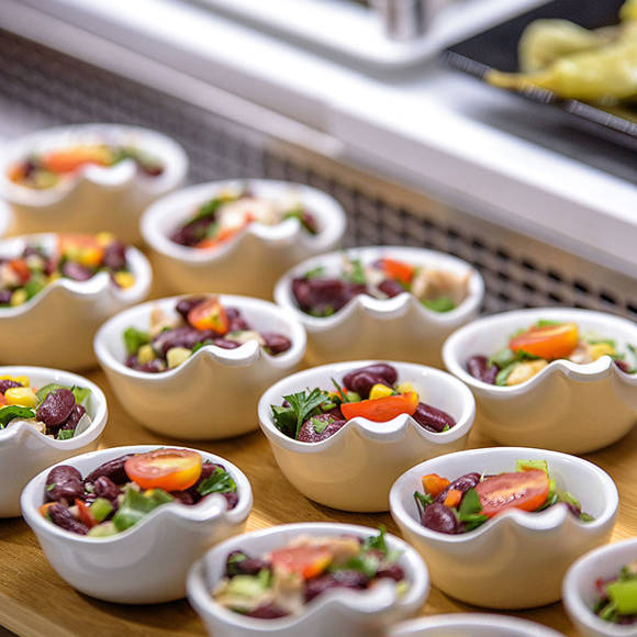 Small ceramic bowls with colorful salad, displayed on a wooden tray