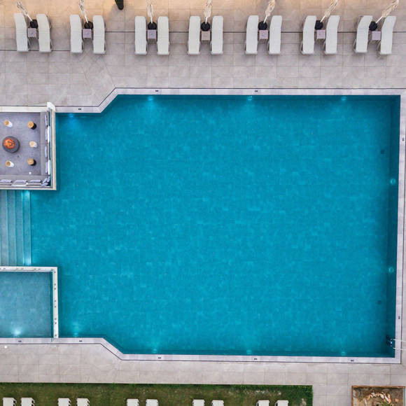 Aerial view of the large outdoor pool area with sunbeds and firepit lounge 