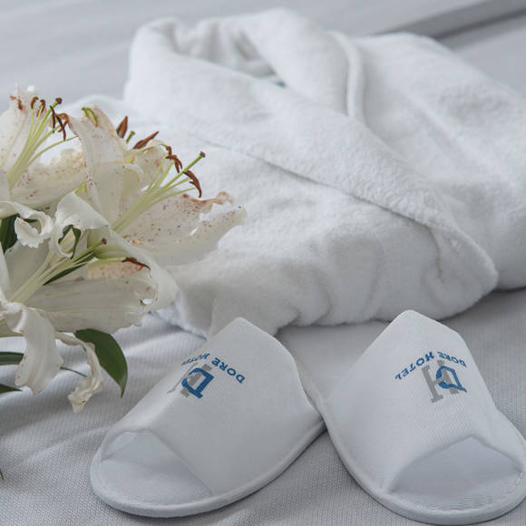 Dore Hotel slippers and bathrobe with fresh white lilies placed on bed