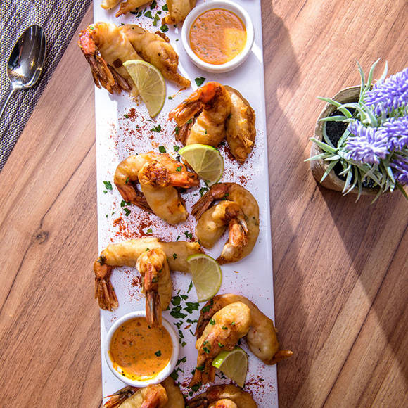 Platter with crispy shrimp, lime wedges and dipping sauce 