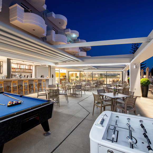 Outdoor entertainment area with a billiard table, foosball table, bar and seating near the pool