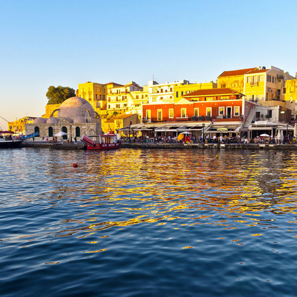 Chania Old Venetian Harbor with waterfront restaurants and shops at sunset