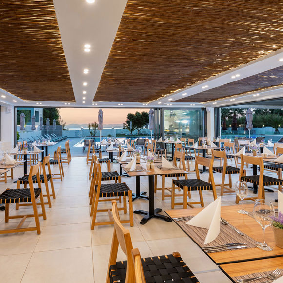 Modern hotel restaurant with set tables and a view of the pool area