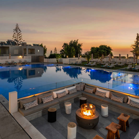 Poolside area at sunset with firepit seating near the pool and scenic lighting 