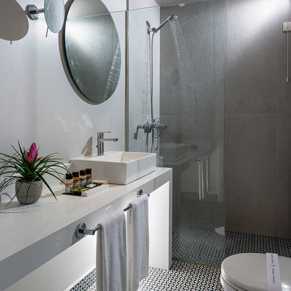 Modern bathroom with walk-in shower, round mirror and patterned flooring