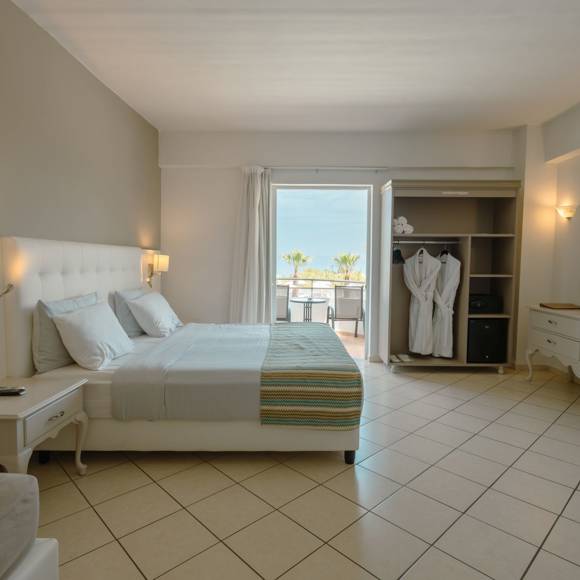 Quadruple room with a double bed, open wardrobe, vanity desk and balcony overlooking the sea