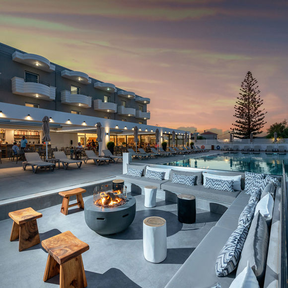Outdoor lounge area with firepit by the pool at sunset