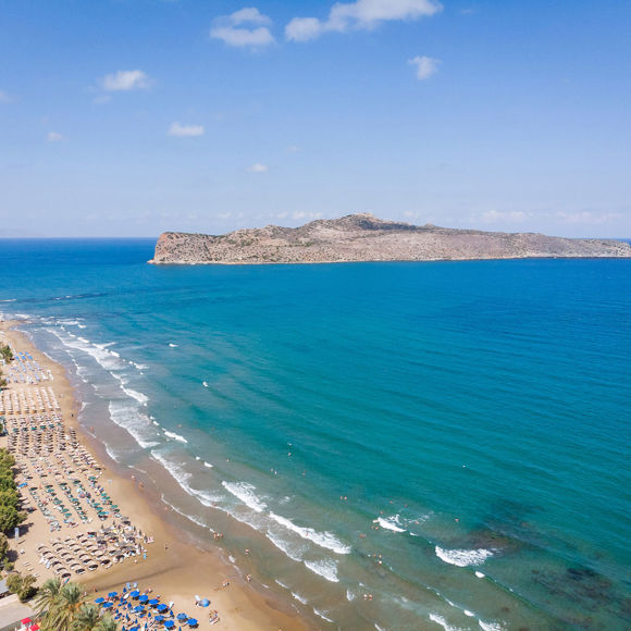 Dore hotel beach with sunbeds, umbrellas, a calm blue sea and view of Theodorou Island