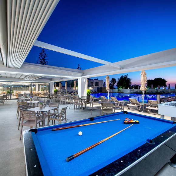 Billiard table and foosball setup on a spacious outdoor terrace with poolside seating 