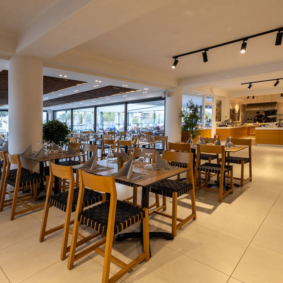 Wide view of the restaurant with set tables, wooden furniture and a visible buffer counter in the background