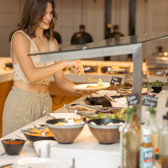 Woman serving herself food at the hotel restaurant buffet counter