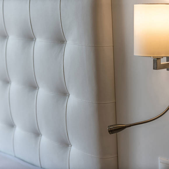 Detail of white tufted headboard with wall-mounted reading lights