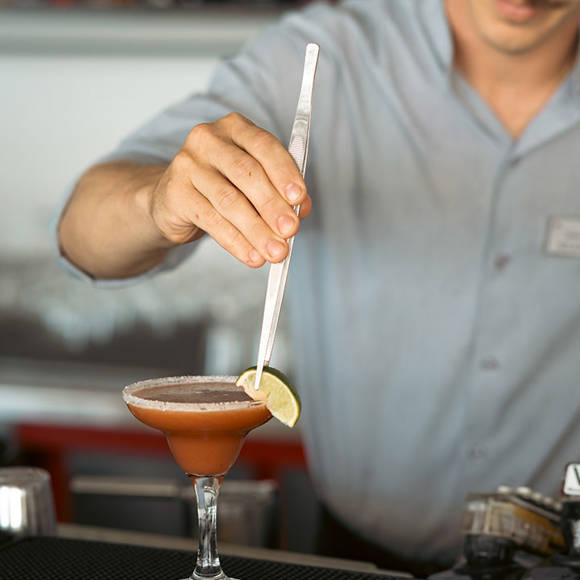 Bartender garnishing a cocktail with a lime slice at the hotel bar